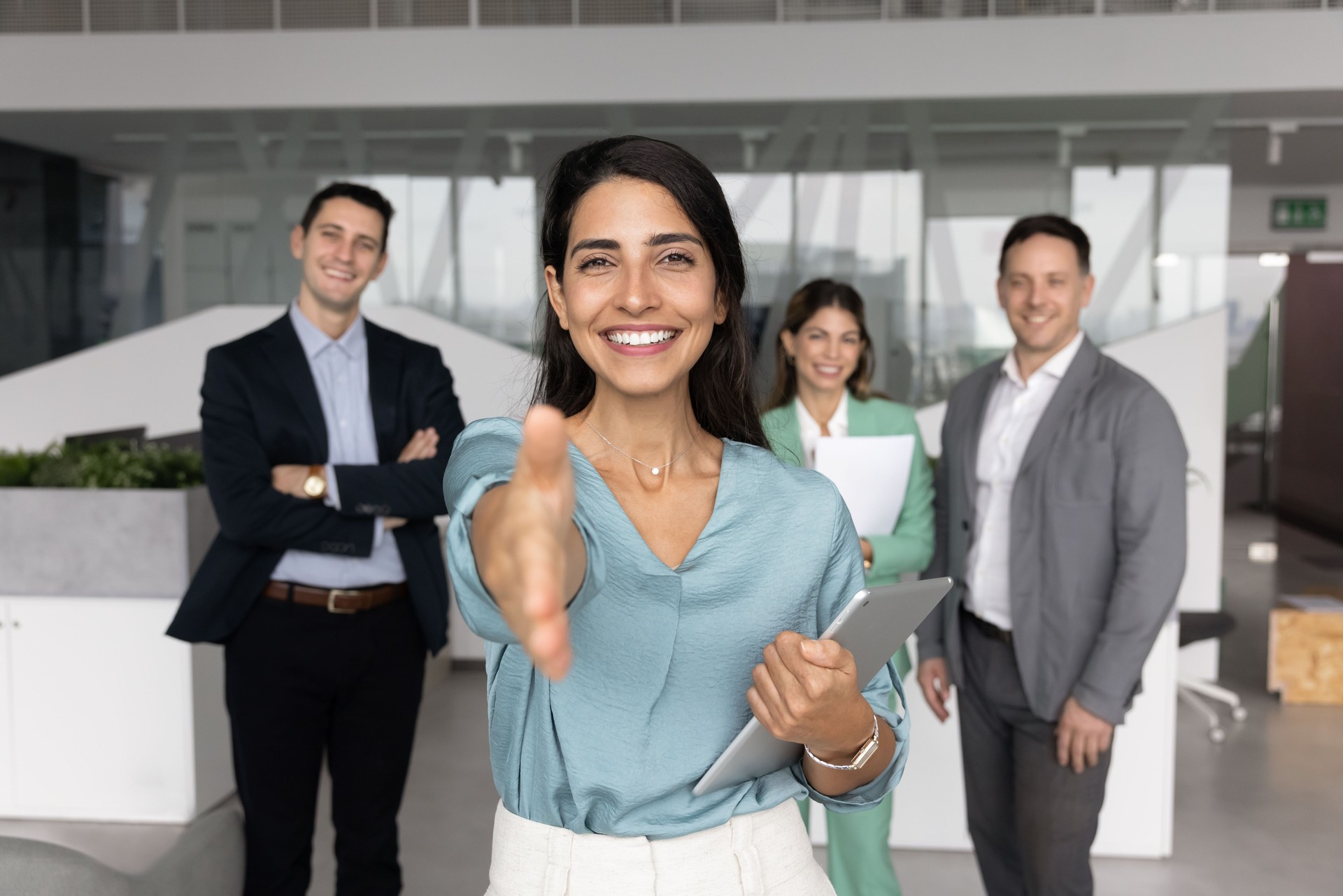 Happy Latin business leader woman offering handshake at camera