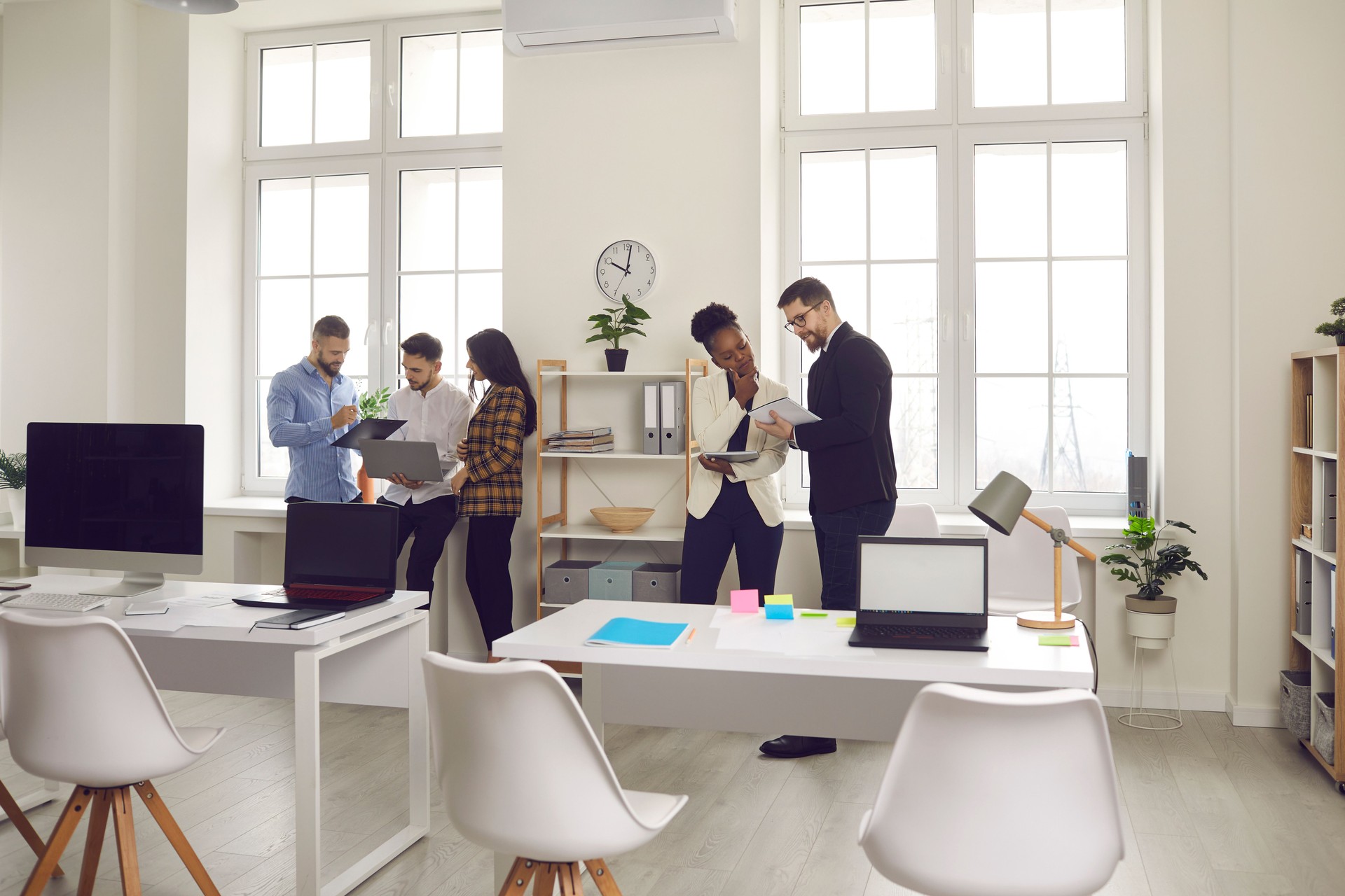 Diverse business team conversation at bright office view from distance